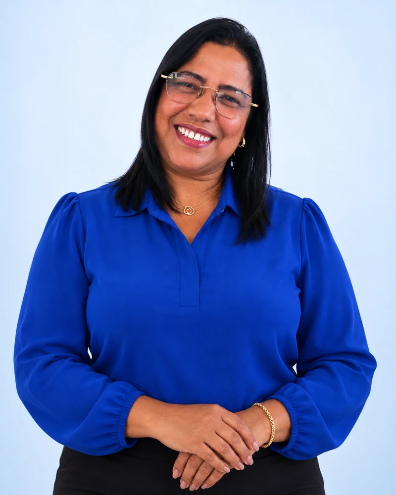 Retrato de Tatiana, sorrindo, com óculos e blusa azul, criado a partir de sua foto no flyer